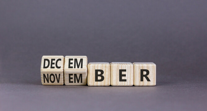 Symbol for the change from November to December. Businessman turns wooden cubes and changes the word November to December. Beautiful grey background. Happy December concept. Copy space.