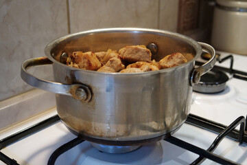 Cooking. Meat is stewing. There is a pot of meat on a gas stove