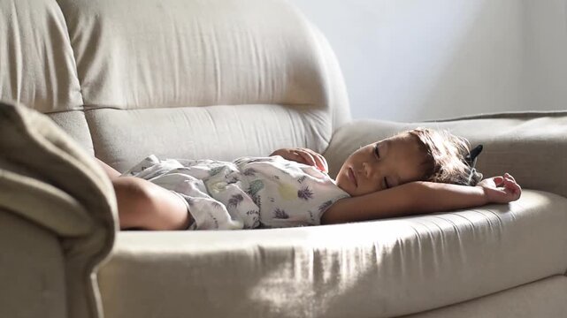 Toddler napping alone on a white couch, airy minimalist scene with bright cozy living room light now