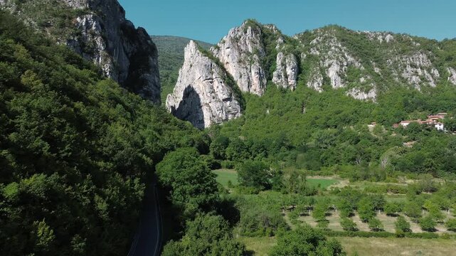 Aerial view of Jerma Canyon in Serbia with a small village surrounded by rocky cliffs and green forest. Horizontal 4k footage