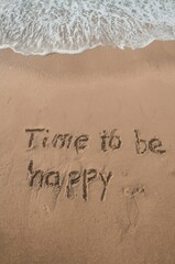 Gentle waves wash over sand with "Time to be happy" written in the sand. The serene scene evokes feelings of peace, relaxation, and a positive outlook. Ideal for themes of vacation, escape, personal g