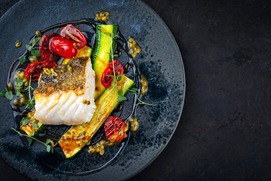 Fried skrei cod white sea fish filet with green vegetable and tomato, rice passion fruit relish umami sauce  Mediterranean dish recipe