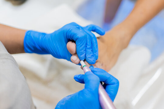 Manicurist working on woman's toenails during pedicure session