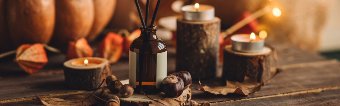 Banner. Aroma reed diffuser, pumpkins, knitted sweaters, candles, dry leaves on wooden table. Concept of house decor, apartment seasonal fragrance. Thanksgiving. Autumn mood, cozy fall home atmosphere