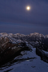 満月の夜明けに初冬の爺ヶ岳を登る人