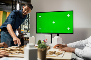 Property engineers team study architectural blueprints with a mockup on TV, collaborating in a smart city urban development master plan. Modern residential project with infrastructure goals.