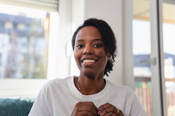 Young Black woman mid-conversation during a video call, expressive and emotionally engaged while speaking to a friend or family member from her home