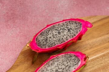 Vibrant dragon fruit halved on wooden board with textured background