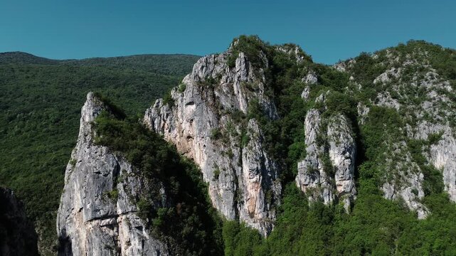 Close aerial view of dramatic rocky cliffs in Jerma Canyon mountains, Serbia country, surrounded by dense forest. Horizontal 4k footage.