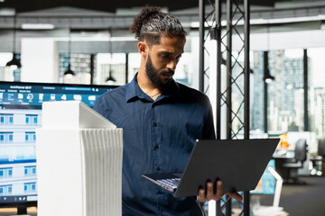 Middle eastern real estate expert analyzing building models for site preparation, studying...
