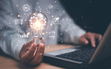 Businessman holding glowing light bulb with digital gear icons and network connections. Representing innovation, artificial intelligence, technology and creative business solutions for future growth.