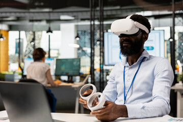 Male analyst in workplace using VR headset to explore futuristic business solutions for corporate efficiency. Black male professional experiencing immersive, ar technology during workday.