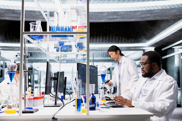 Molecular biologist uses computer program displaying DNA data analysis interface in laboratory. African american man using bioinformatics genomics software on PC in sterile lab environment