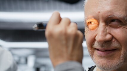 Woman medic using light pen to examine senior patient for clinical trial observation in a research institute, study patient reactions to new pills. Monitoring treatment effects. Camera B.