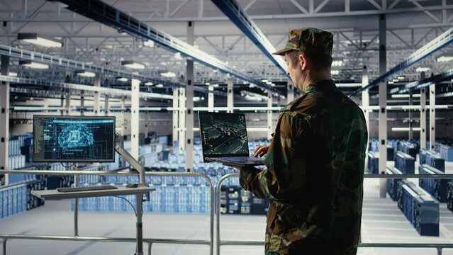 Military engineer in data center tracking satellite coordinates using laptop interface. Soldier in server room analyzing reconnaissance data through satellite imaging systems, camera A - Powered by Adobe