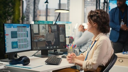 Businesswoman participates at web chat event with a shareholder, sharing insight on performance metrics for a briefing. Video conferencing in the office between business associates. Camera B.