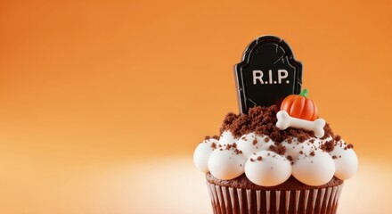 Spooky Halloween cupcake with tombstone, pumpkin, and bone decorations on bright orange background ready for holiday dessert party treats