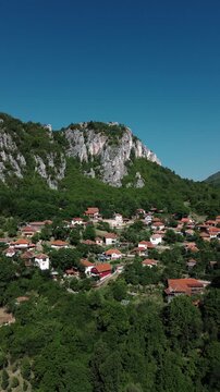 Aerial view of Jerma Canyon in Serbia with a small village surrounded by rocky cliffs and green forest. Vertical 4k footage