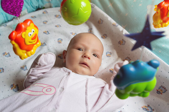 Happy baby lying down interacting with hanging toys