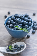 Close-up of wild blueberries on a black velvet background and a sterling silver spoon with decorative engravings