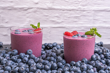 Mound of bright blueberries and a blueberry and vegan protein smoothie on a Nordic pine table