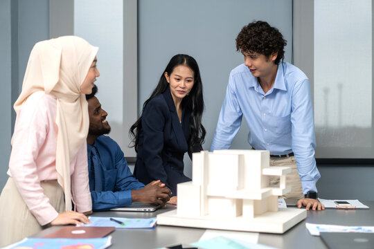 Architects engineers collaborating on building design project in modern office, diverse team of professionals female muslim architect and male engineers discussing architectural model of structure - Powered by Adobe
