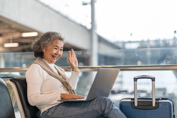 Senior woman working on laptop at airport terminal enjoying online connection, travel lifestyle and...