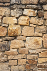 Obraz premium Textured stone wall composed of various sizes of natural stones in shades of beige and brown, showcasing rustic charm and durability in architectural design
