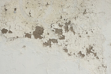 Textured wall surface with peeling paint and rough patches, showcasing a weathered appearance and natural imperfections, ideal for backgrounds or artistic projects