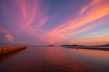 The tranquil lake reflects the fiery hues of sunset, where orange, pink, and violet merge into calm waters. Gentle ripples shimmer beneath a peaceful sky capturing the serene beauty of nature.