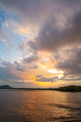 Golden sunlight stretches across still waters. glowing gently against distant mountains. The calm atmosphere and colorful reflections evoke serenity. making the lake a perfect sanctuary in sunset