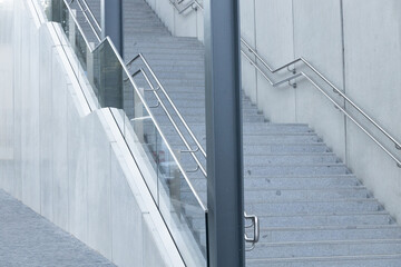 Modern concrete staircase with sleek metal railings and glass panels, leading upwards in a contemporary architectural setting, showcasing minimalistic design and urban aesthetics