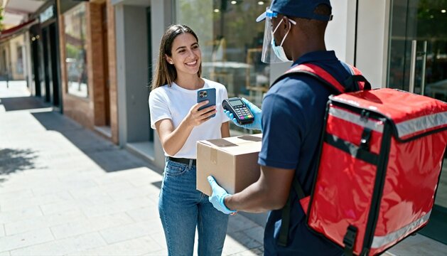 Happy woman using smartphone for contactless payment on delivery. Customer paying courier for package with NFC technology. E-commerce and safe shopping concept with man in mask.