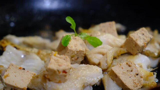 Seasoned Cod fillets and Tofu with spices and sun-dried tomatoes. On Stovetop, iron cast skillet, close up boiled oil, process deep fried.