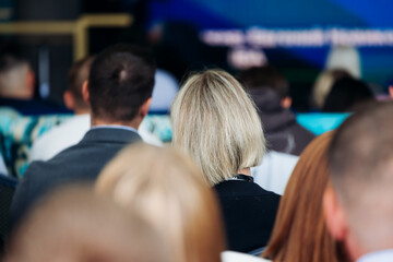 Audience at the modern conference hall listens to panel discussion, people on a congress together...