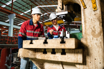 Engineering instructor guiding apprentice in machine operation during industrial training at...