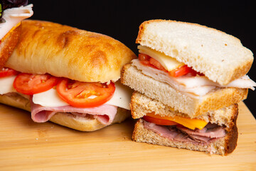 stacked cold meat deli sandwiches on cutting board