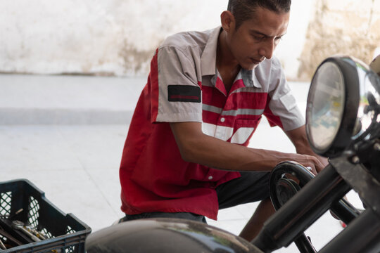 Mechanic man repairing motorcycle in garage workshop - Powered by Adobe
