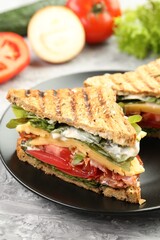 Tasty sandwiches with bacon, cheese, vegetables and sauce on grey textured table, closeup
