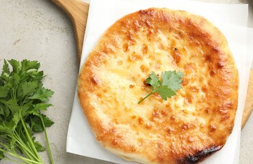Delicious Megrelian khachapuri with parsley on grey table, top view