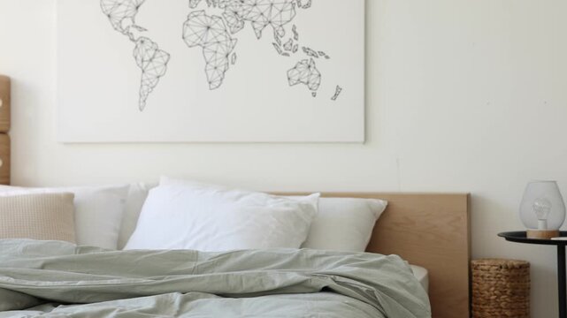 Cozy large bed with linens, side table and lamp near white wall in bedroom, camera moving left