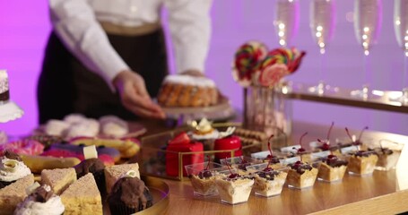 Waiter arranging desserts at buffet table, closeup