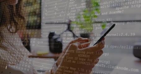 Holding smartphone, female coder scanning ports at desk with monitor and coffee mug, copy space