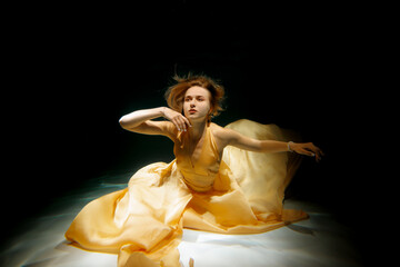 Fototapeta premium An Elegant and Ethereal Underwater Dance Performance Featuring a Stunning Beautiful Yellow Gown