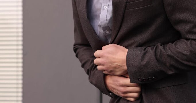 Young man in suit suffering from stomach ache and nausea outdoors, closeup