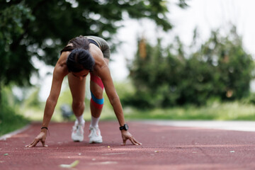 Athlete Warming Up on a Track Field Wearing Sports Tape and Preparing to Start a Sprint