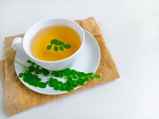 Moringa or Daun kelor herbal drink. A cup of Moringa tea. Boiled moringa leaves water in cup on white background. Healthy drink lifestyle