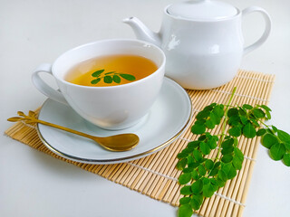 Moringa or Daun kelor herbal drink. A cup of Moringa tea. Boiled moringa leaves water in cup on white background. Healthy drink lifestyle