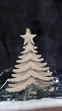 Una toma de cerca de un &aacute;rbol dorado rodeado de luces blancas con un fondo desenfocado. Decoraci&oacute;n de navidad y fin de a&ntilde;o. Video Vertical