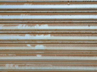 The image shows a weathered, metallic roller shutter door, also known as a roll up door